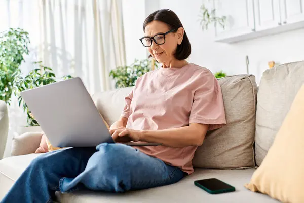 Woman in cozy homewear using laptop on couch. — Stock Photo