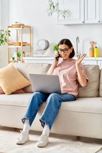 A mature woman in stylish homewear sits on a couch, absorbed in her laptop. — Stock Photo