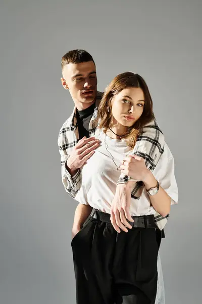 A young man and woman strike a pose together in a studio setting against a grey background, exuding love and intimacy. — Stock Photo