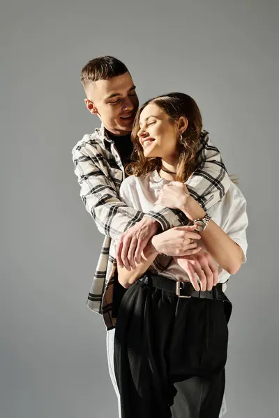 A man tenderly holds a woman in his arms, showing love and affection in a studio setting against a grey background. — Stock Photo