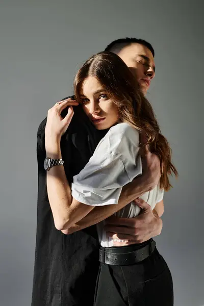 A man and a woman in a loving embrace, expressing closeness and affection in a studio setting against a grey background. — Stock Photo
