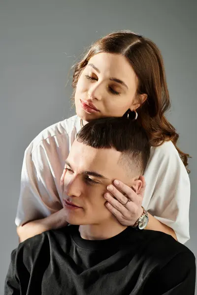 A young man and woman, deeply in love, elegantly pose together in studio with a grey background. — Stock Photo
