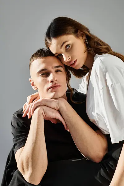 A man and a woman are striking a pose together in a studio with a grey background. — Stock Photo