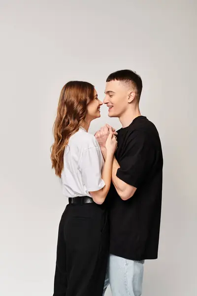 A young couple in love, standing side by side in a studio against a grey background. — Stock Photo