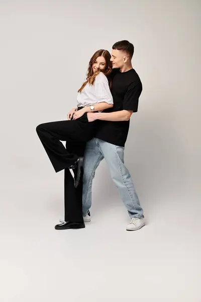 A man tenderly holds a woman in his arms, expressing love and affection in a studio setting with a grey background. — Stock Photo