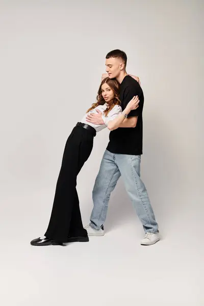 A young couple in love dancing gracefully in a studio with a grey background. — Stock Photo