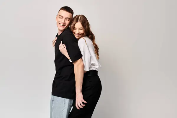 Un jeune couple amoureux debout côte à côte dans un studio avec un fond gris. — Photo de stock