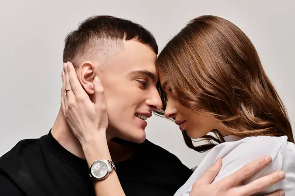 A young man and woman tenderly embrace each other in a studio setting with a grey background. — Stock Photo