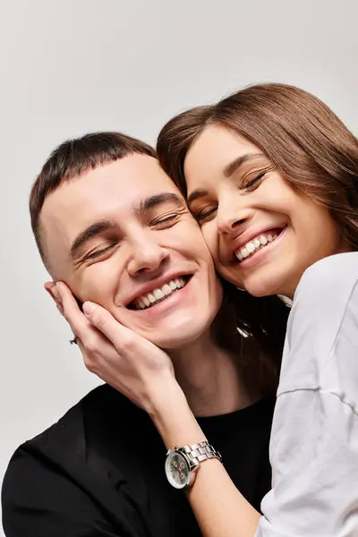 A man and woman sharing a heartfelt hug, showing love and affection in a studio setting with a grey background. — Stock Photo