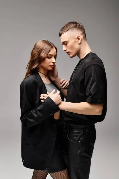 A man and a woman standing closely together in a studio with a grey background, radiating love and togetherness. — Stock Photo