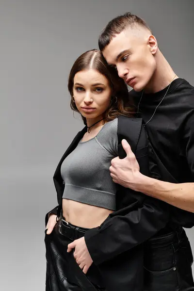 A young couple standing closely next to each other in a studio with a grey background, showing love and togetherness. — Stock Photo