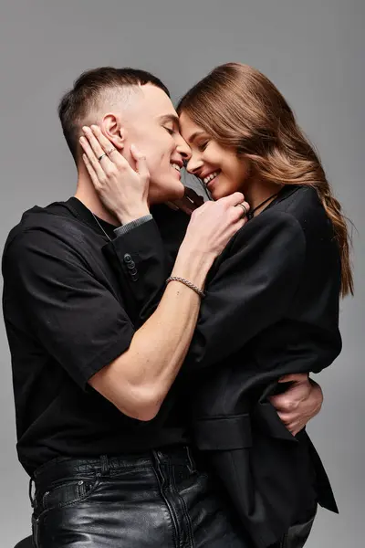 A young man and woman deeply embrace each other in a studio setting with a grey background. — Stock Photo