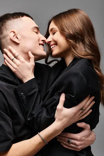 Ein Mann und eine Frau, ein junges Paar, umarmen sich in liebevoller Geste vor grauem Hintergrund. — Stockfoto