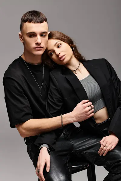 Um homem e uma mulher, um jovem casal apaixonado, sentam-se ao lado um do outro em um estúdio com um fundo cinza. — Fotografia de Stock