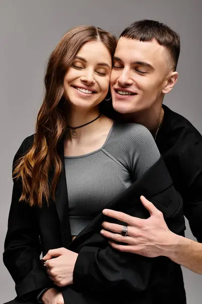 Um jovem e uma mulher abraçam-se amorosamente em um estúdio com um fundo cinza. — Fotografia de Stock