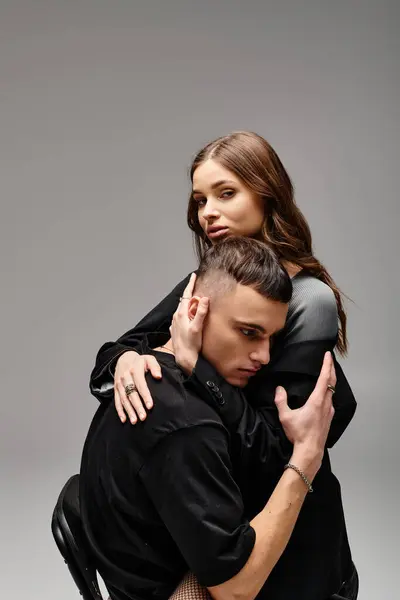 A man tenderly embraces a woman in a chair, their bodies intertwined, conveying a sense of love and intimacy. — Stock Photo
