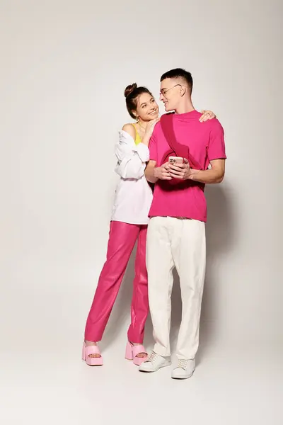 A stylish young couple in love stands together in a studio, against a grey background, exuding elegance and unity. — Stock Photo