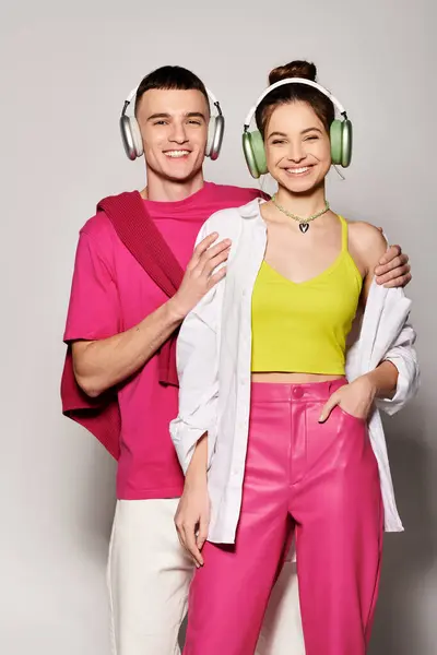 Um jovem casal elegante, profundamente apaixonado, ouvindo música juntos usando fones de ouvido em um cenário cinza elegante. — Fotografia de Stock