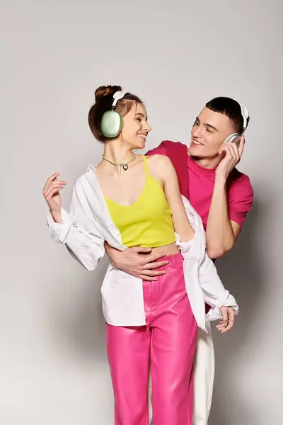 A stylish young man and woman stand side by side, exuding love and togetherness in a studio with a grey background. — Stock Photo