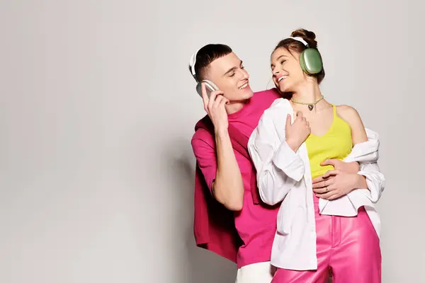 A stylish young couple in love standing together in a studio, against a grey background. — Stock Photo