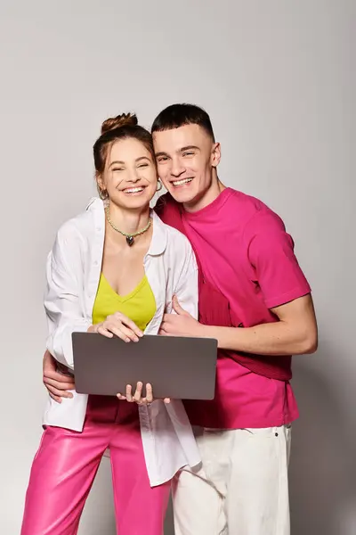 A stylish young couple in love stands together in a studio with a grey background. — Stock Photo