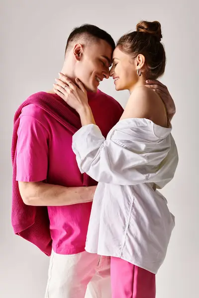 Un homme et une femme, élégamment vêtus, se tiennent côte à côte dans un studio sur un fond gris, se regardant avec amour. — Photo de stock