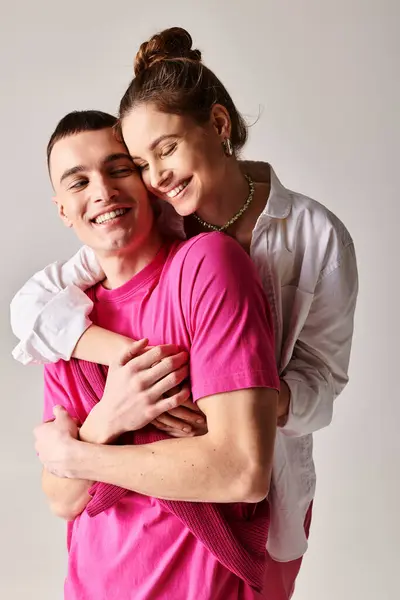 Um jovem e elegante casal apaixonado apaixonadamente abraçando um ao outro em um estúdio, com um fundo cinza. — Fotografia de Stock
