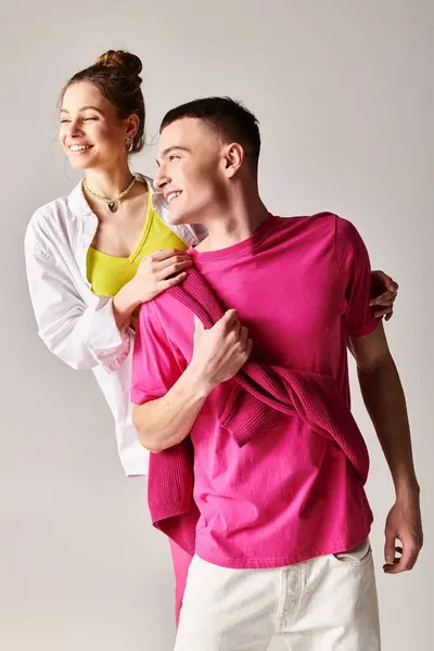 Um jovem casal elegante se coloca em abraço contra um cenário de estúdio cinza, exalando amor e conexão. — Fotografia de Stock