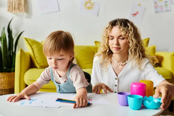 Una donna con i capelli ricci siede a un tavolo con sua figlia, impegnandosi in attività di apprendimento Montessori a casa.. — Foto stock