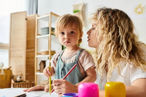 A curly mother and her toddler daughter engage in the Montessori method of education at a table. — Stock Photo