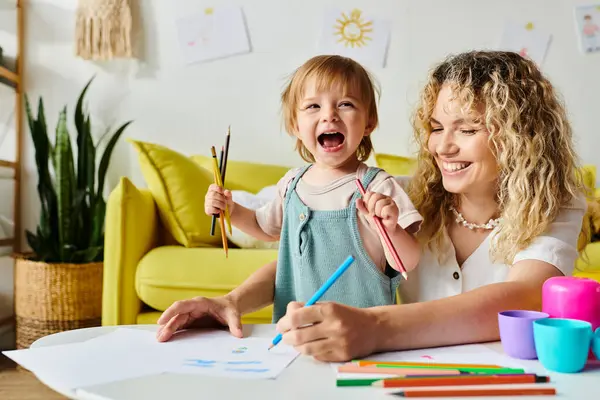 Eine lockige Mutter und ihre kleine Tochter machen Montessori-Unterricht an einem Tisch in gemütlicher häuslicher Umgebung. — Stockfoto