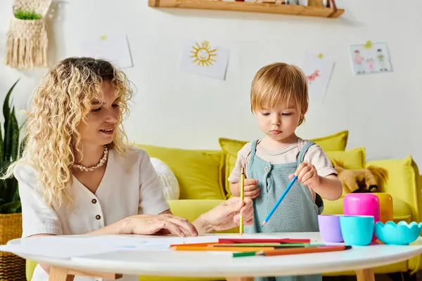 Une femme aux cheveux bouclés et sa petite fille assise à une table, engagées dans des activités éducatives Montessori ensemble. — Photo de stock