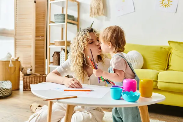 Une mère aux cheveux bouclés et sa petite fille s'assoient à une table, engagés dans des activités Montessori pour favoriser l'éducation des jeunes enfants. — Photo de stock