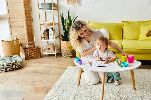 A curly mother and her toddler daughter engage in Montessori activities at a table in a warm and inviting living room setting. — Stock Photo
