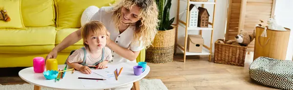 A mother with curly hair and her toddler daughter engaged in Montessori learning at a table at home. — Stock Photo