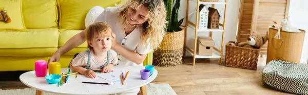 Eine Mutter mit lockigem Haar und ihre kleine Tochter beim Montessori-Lernen am heimischen Tisch. — Stockfoto