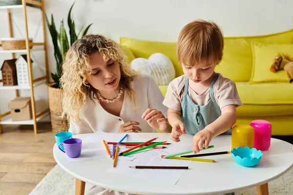 Uma mãe encaracolada e sua filha criança sentam-se em uma mesa usando lápis de cor para a educação Montessori. — Fotografia de Stock