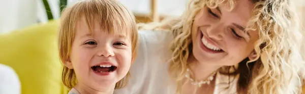 Una madre rizada y su hija pequeña comparten un momento de alegría y risa mientras se dedican a la educación Montessori en el hogar. - foto de stock