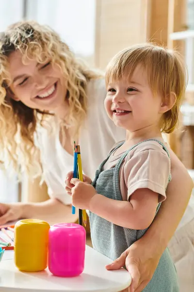 A curly mother and her toddler daughter engage in playful exploration with crayons using the Montessori education method at home. — Stock Photo