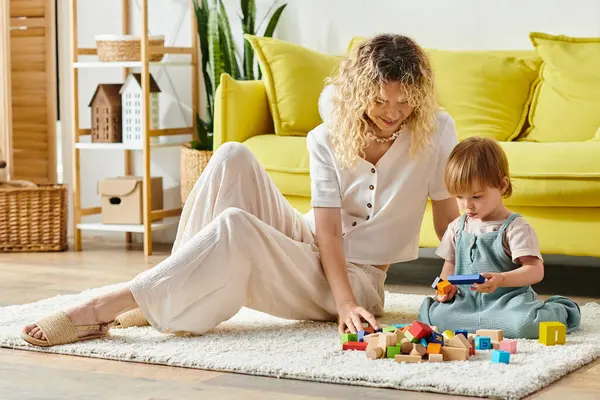 A woman with curly hair playing with her toddler daughter on the floor, engaging in Montessori-style education and bonding. — Stock Photo