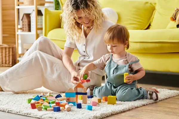 A curly-haired mother engages in playful Montessori activities with her toddler daughter on the floor at home. — Stock Photo