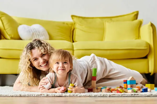 A curly mother and her toddler daughter engage in Montessori learning, sprawled comfortably on the floor at home. — Stock Photo
