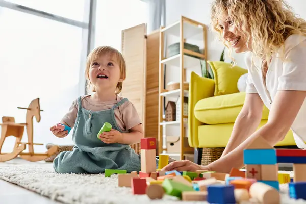 Curly mother engaging with her toddler daughter on the floor, practicing Montessori educational activities together at home. — Stock Photo