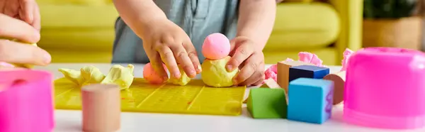 Enfant heureux de jouer avec divers jouets et de s'engager dans des activités imaginatives sur une table à la maison. — Photo de stock