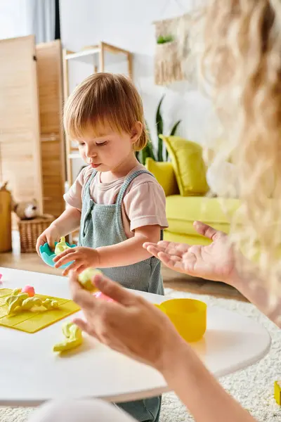Eine lockige Mutter und ihre kleine Tochter spielen fröhlich mit Spielzeug und umarmen die Montessori-Pädagogik zu Hause. — Stockfoto