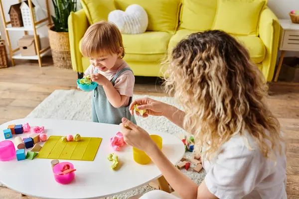 Eine Frau mit lockigem Haar und ihre kleine Tochter, die sich intensiv für Montessori engagiert, spielen zu Hause mit buntem Spielzeug. — Stockfoto