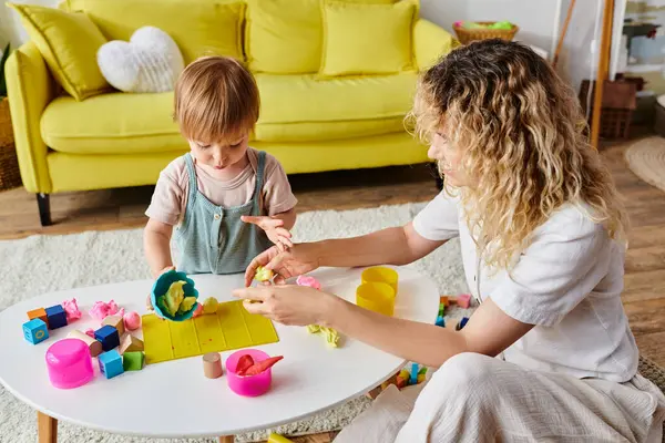 Eine lockige Mutter spielt mit ihrer kleinen Tochter Montessori-Spiele und erkundet gemeinsam Spielzeug in einem warmen Zuhause. — Stockfoto