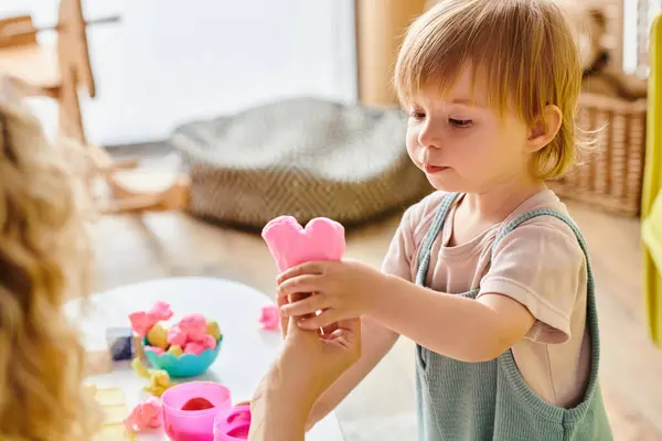 A curly mother empowers her toddler daughter in Montessori play with a colorful, educational toy. — Stock Photo