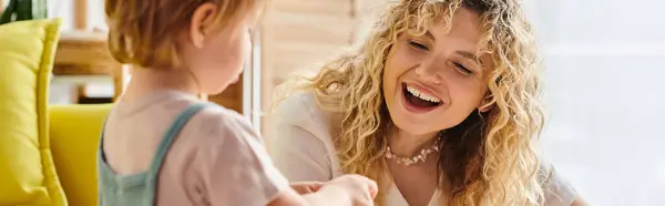A curly mother shares a laugh with her Montessori toddler daughter during an engaging conversation at home. — Stock Photo