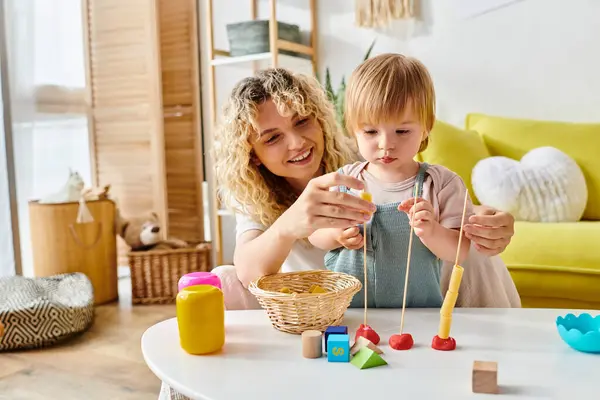 Eine lockige Mutter und ihre kleine Tochter lernen zu Hause spielerisch mit Holzspielzeug und genießen die Montessori-Pädagogik. — Stockfoto